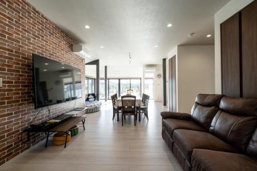 a living room with a couch and a brick wall at 大型貸切別荘 HOUSE ASA 最大22名 サウナ BBQ ホームカラオケ 焚き火 from九十九里海岸歩7分 in Kujukuri