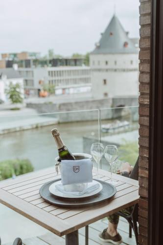 a bottle of champagne on a table with wine glasses at Cobergher Hotel in Kortrijk