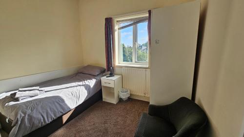 a bedroom with a bed and a chair and a window at ABBEY HOTEL in Stafford
