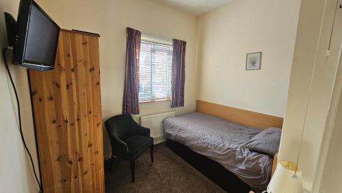 a small bedroom with a bed and a chair at ABBEY HOTEL in Stafford