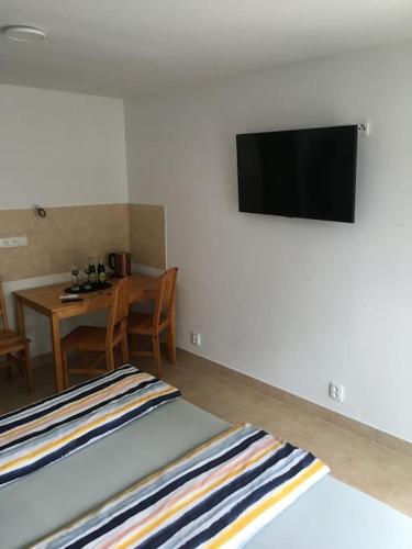 Habitación con cama y TV en la pared. en Apartmány U Hadiny en Humpolec