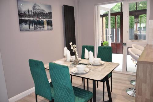 Modern 3 bedroom house- 2 parking spaces- near central MK في Shenley Lodge: غرفة طعام مع طاولة وكراسي خضراء