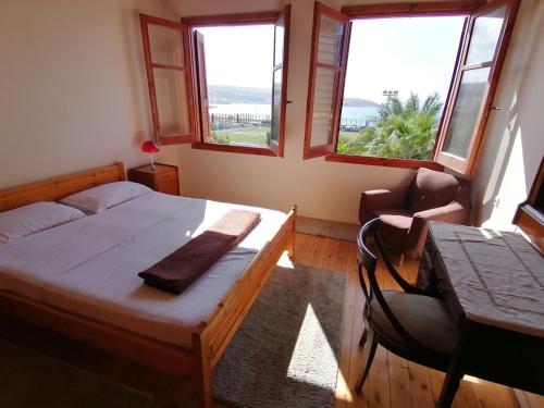 a bedroom with a bed and a table and two windows at Home of sunset in Rethymno