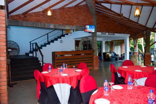 un restaurante con mesas y sillas rojas y una escalera en Araliya, en Kekirawa