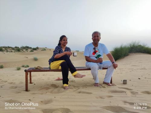 a man and woman sitting on a bench in the sand at The Elite Castle in Jaisalmer