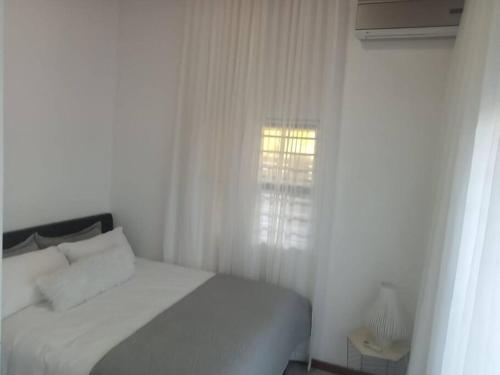 1 dormitorio con cama blanca y ventana en Two bedroom flatlet in Panorama, en Ciudad del Cabo