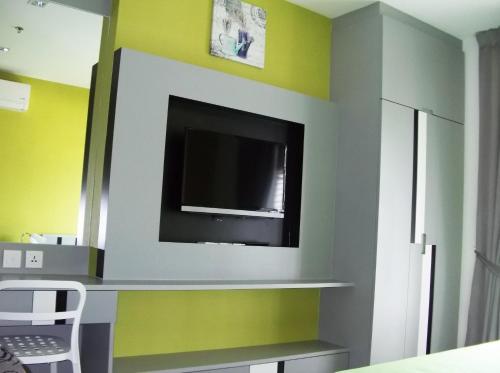 ein Wohnzimmer mit einem TV und gelben Wänden in der Unterkunft Sukhumvit 81 in Bangkok