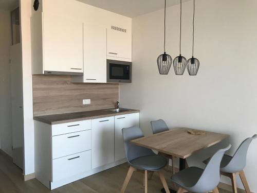 een keuken met witte kasten en een houten tafel en stoelen bij Work or holiday nieuw studio Santhooft in Nieuwpoort