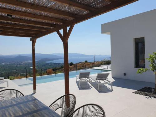 a patio with a table and chairs and a pool at Villa Eleni Nafplio, pool & sea view in Tolo