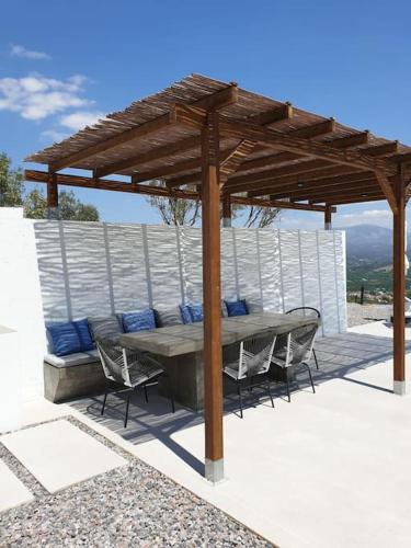 a table and chairs under a wooden pergola at Villa Eleni Nafplio, pool & sea view in Tolo