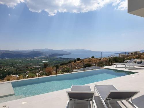 a swimming pool with chairs and a view of the water at Villa Eleni Nafplio, pool & sea view in Tolo
