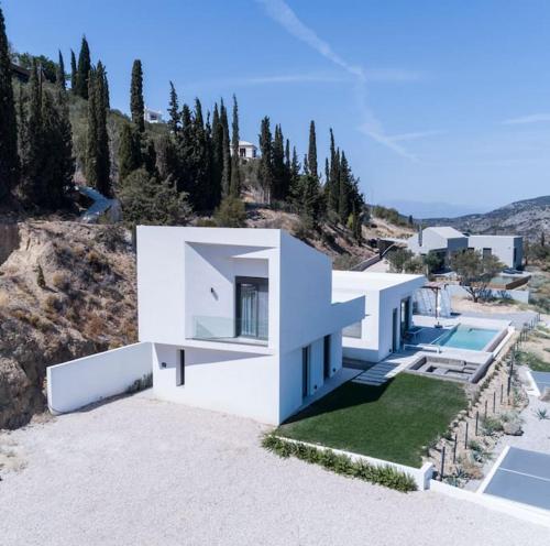 a white house on a hill with a swimming pool at Villa Eleni Nafplio, pool & sea view in Tolo