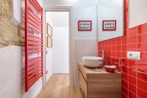 La salle de bains est pourvue d'un lavabo blanc et de carreaux rouges. dans l'établissement CHARMING HOUSE con doccia sensoriale e cortile interno - CENTRO STORICO, à Cagliari
