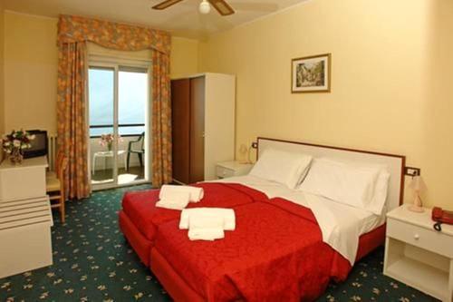 Schlafzimmer mit einem roten und weißen Bett und einem Fenster in der Unterkunft Village Bazzanega - Montagnoli Group in Tremosine sul Garda