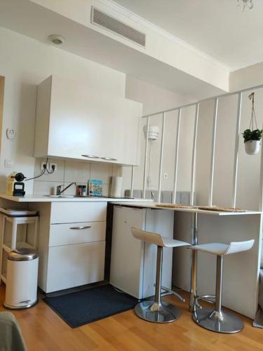 une cuisine avec des placards blancs et deux tabourets de bar dans l'établissement Charmant Studio Quai Joliette, à Marseille