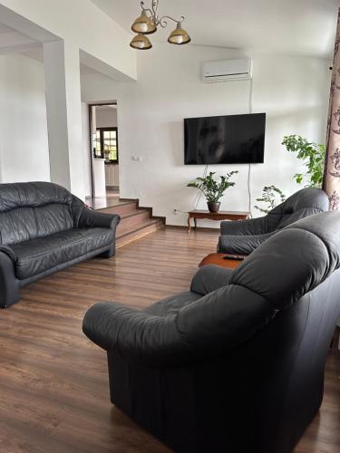 a living room with two black couches and a flat screen tv at Pensiunea Emelys in Iaşi