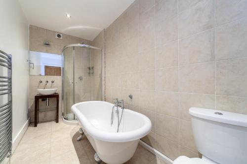 a bathroom with a tub and a toilet and a sink at The Wandsworth Flat in Bromley