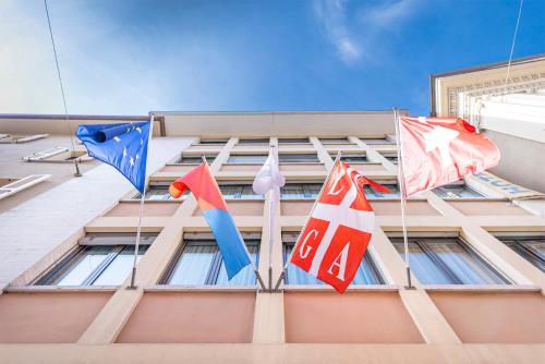 three flags on the side of a building at San Carlo Apartments in Lugano