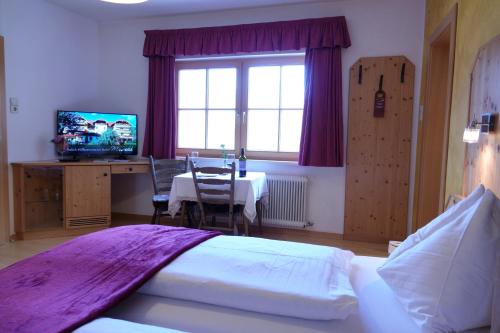 a bedroom with a bed and a table and a television at Hotel Malteinerhof in Malta