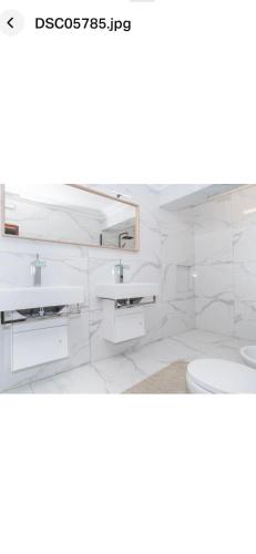 bagno bianco con 2 lavandini e servizi igienici di Faustina's room a Portimão