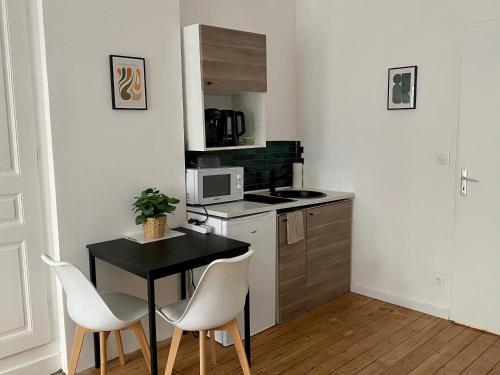 a small kitchen with a black table and white chairs at Hortensia*Proche Centre-Ville et CHU*Parking in Amiens