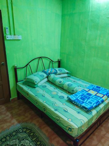 een bed met blauwe en groene lakens en kussens bij Iman homestay in Lunas