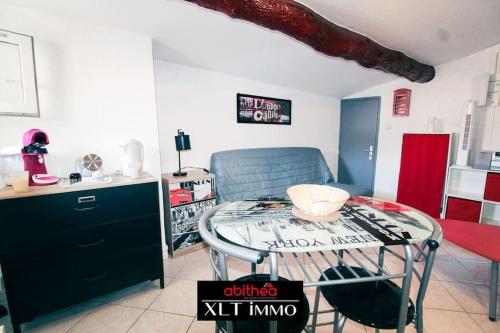 a living room with a glass table and a kitchen at Studio île Martigues in Martigues