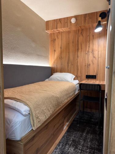 a small bedroom with a bed and a table at AQ Capsule Hotel in Almaty