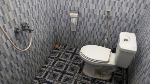 a bathroom with a toilet in a tiled wall at Dannu's Homestay Ijen and Bromo Tour in Banyuwangi