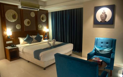 een hotelkamer met een bed en een blauwe stoel bij Annex Suites Bogra - CityCentre in Bogra