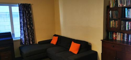 a living room with a black couch with orange pillows at Bluewater Lodge in Napier