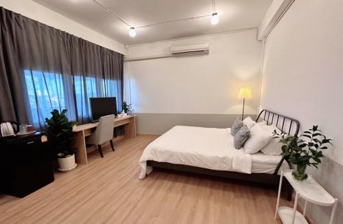 a bedroom with a bed and a desk with a computer at La Moon House in Salaya
