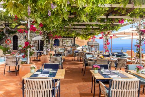 a restaurant with tables and chairs with the ocean in the background at Hotel Punta Tragara in Capri