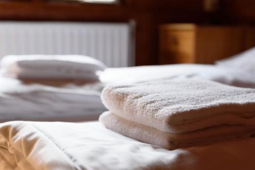 a stack of white towels sitting on top of a bed at Spacious wooden cottage with infra-red sauna at Veluwe in Putten