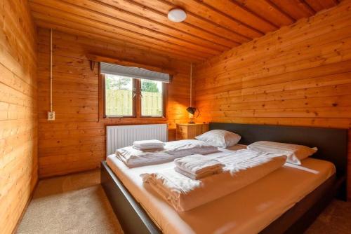 una camera con un letto in una cabina di legno di Spacious wooden cottage with infra-red sauna at Veluwe a Putten