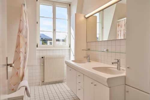 a white bathroom with two sinks and a mirror at City Apartment Bern, perfect located and spacious in Bern