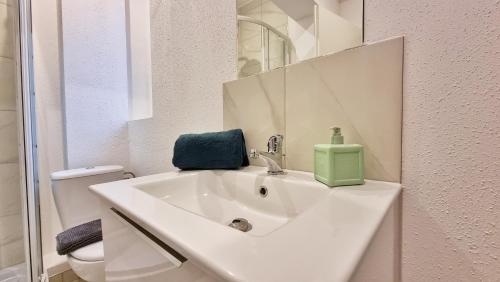 La salle de bains est pourvue d'un lavabo blanc et d'un distributeur de savon vert. dans l'établissement La Résidence Évasion 1 - Original - Gare - Wifi - Relax BNB, à Mulhouse