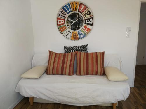 a clock on the wall above a couch with pillows at Gästezimmer mit eigenem Bad in Reihenmittelhaus in Feucht