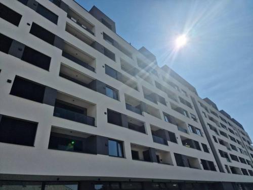 a white apartment building with the sun in the background at Stylish Urban Residence with parking spot in Nivy