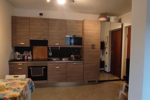 una cocina con armarios de madera y una mesa en una habitación en Accogliente monolocale con piscina, en Caronno Pertusella