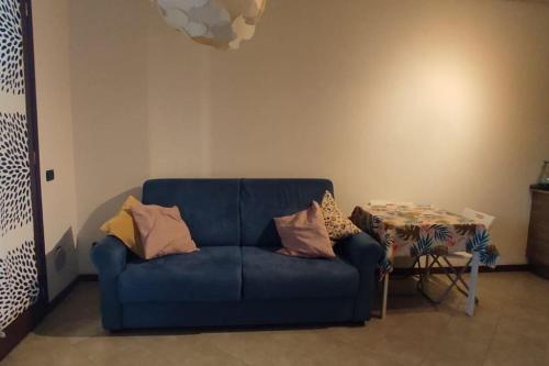 Sofá azul sentado en una sala de estar con mesa en Accogliente monolocale con piscina, en Caronno Pertusella