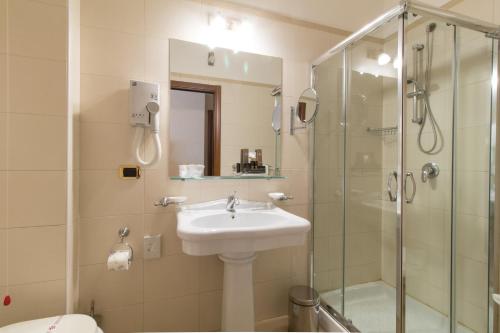 uma casa de banho com um lavatório e uma cabina de duche em vidro. em Hotel Federico II em Enna