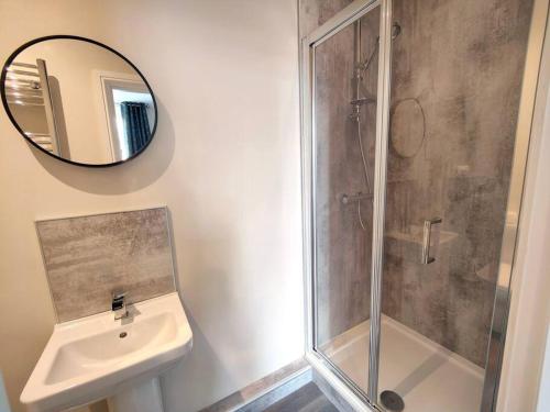 ein Bad mit einer Dusche, einem Waschbecken und einem Spiegel in der Unterkunft Carvetii - ANNE House Room 1 - Dbl bed Ground floor en-suite in Carlisle