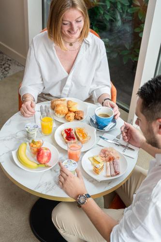 un homme et une femme assis à une table avec une assiette de nourriture dans l'établissement Le Mauritia Hotel et Spa, à Pornic