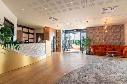 a living room with an orange couch in a room at Le Mauritia Hotel et Spa in Pornic