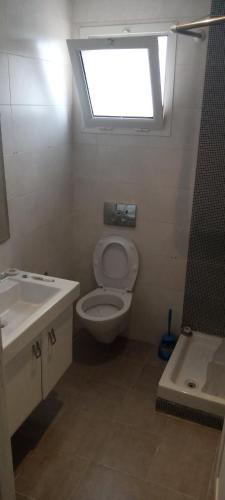 ein Bad mit einem WC, einem Waschbecken und einem Fenster in der Unterkunft Appartement luxeuse in Nassene Srhira