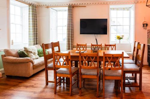 a dining room with a table and chairs and a couch at Albert's Place in Weymouth