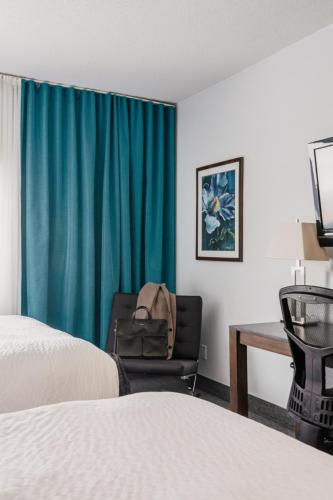 a room with a bed and a chair and a desk at Riotel Matane in Matane