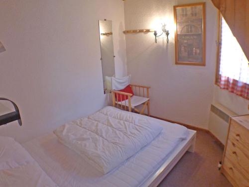 - une petite chambre avec un lit blanc et une chaise dans l'établissement Charmant T2 avec mezzanine au cœur de Samoëns dans la résidence Les Campannes - FR-1-629-68, à Samoëns