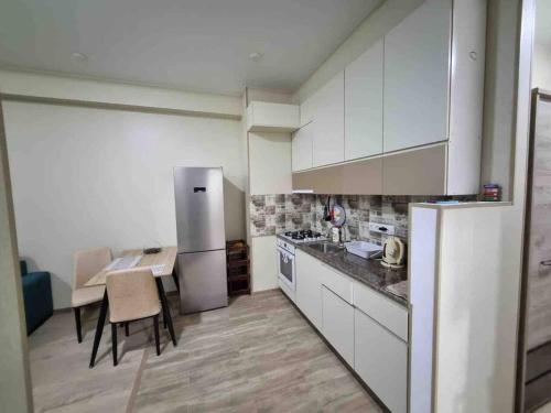 a kitchen with white cabinets and a table and a refrigerator at Recently built, new apartment Tbilisi in Tbilisi City